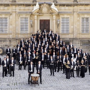 an orchestra stands on the steps and in the courtyard of a pale stone building