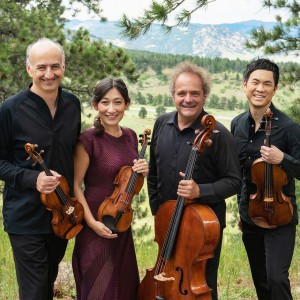 outdoors in a mountain meadow, a string quartet holds their instruments